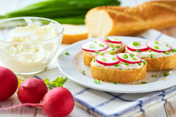 istock Cutting baguette with soft cream cheese and radish on a light kitchen table. Tasty summer snacks. 2183193069