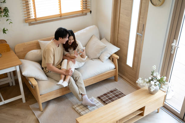istock Loving asian couple sharing a cozy moment while browsing on smartphone at home 2183193084
