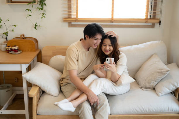 istock Happy young couple enjoys relaxed time together, using smartphone on couch 2183193085