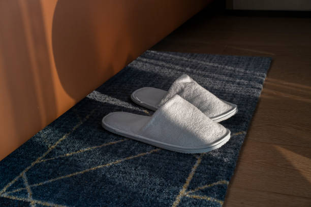 A pair of used clogs or sandals of synthetic material on a coloured cobbled cement surface