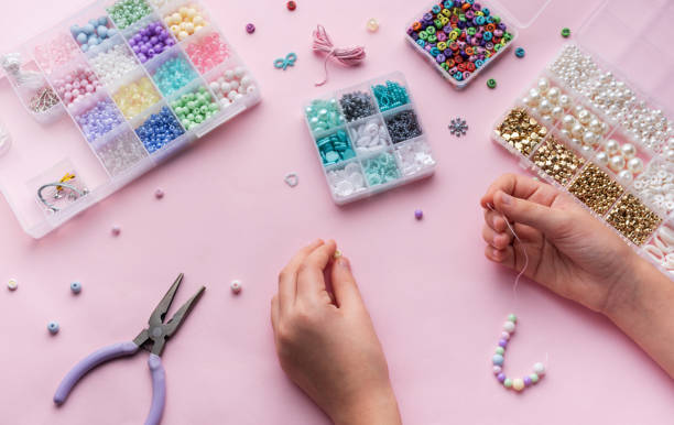 istock Creating colorful beaded jewelry with assorted beads and crafting tools on a light pink surface 2183207472