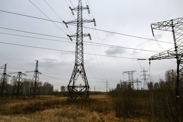 High voltage transmission line supports and wires against a cloudy sky. Power supply
