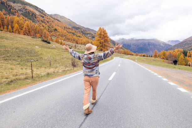 istock Woman Strolling Down an Autumn Road with Arms Open 2183212213