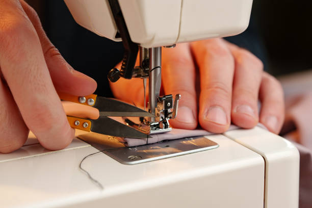 istock Hands sewing fabric using a sewing machine on a wooden table in a well-lit workspace 2183216164