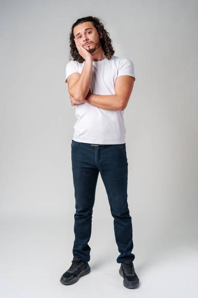 istock A young man stands thoughtfully against a plain background, expressing contemplation 2183216536