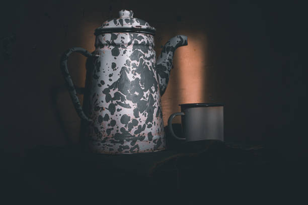 An enamel mug and teapot in a low light place