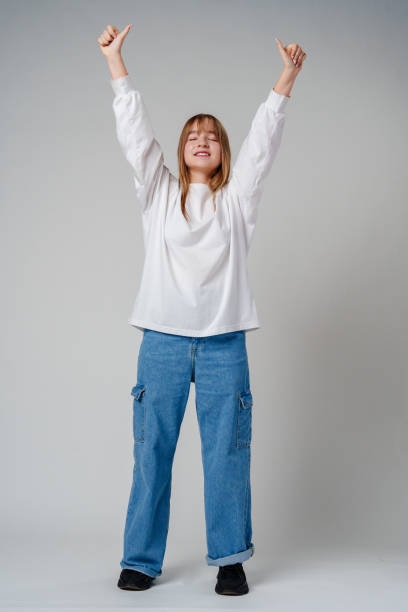istock A joyful young girl with long hair wearing a white sweater stands against a plain background 2183217607