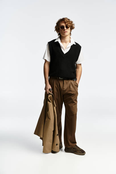 Stylish young man in autumn attire posing confidently in a modern studio setting