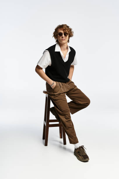 istock Stylish young man in autumn attire poses confidently in modern studio setting 2183218092