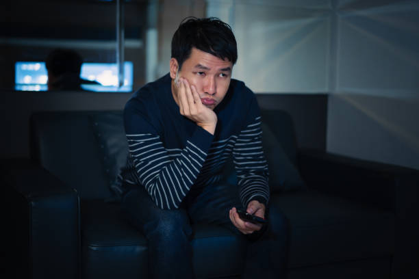 istock bored man watching TV on sofa at night 2183218232
