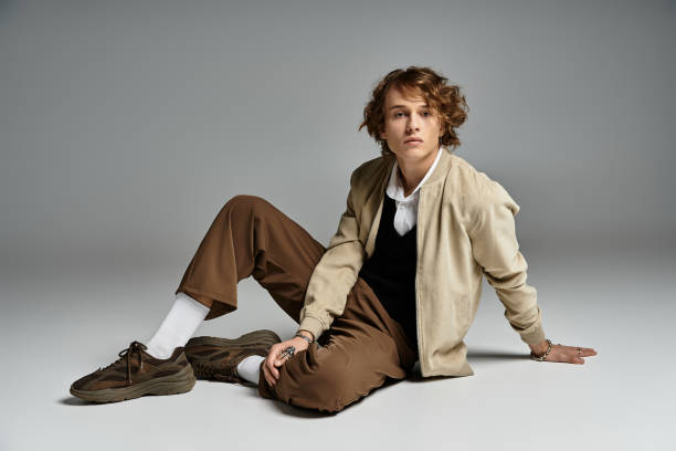 A stylish young man showcases autumn fashion in a modern studio setting