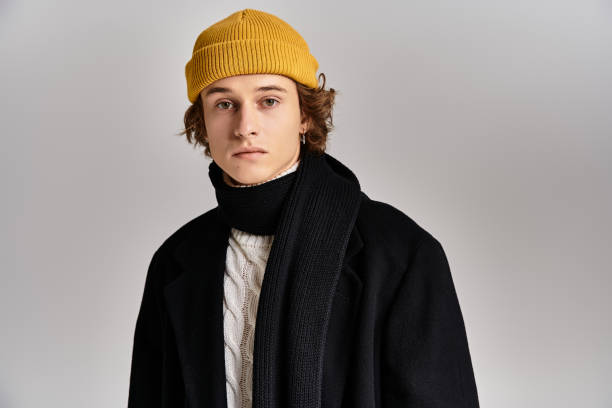 istock A young man in a black coat and yellow beanie poses elegantly in a modern studio 2183220546