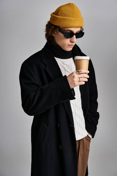 istock A young man in a black coat and yellow beanie poses with coffee in a studio 2183220933