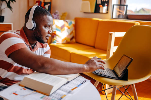 istock Young male adult student studying at home in living room using digital tablet while sitting on floor 2183224593