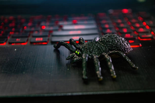 istock A black toy spider with green eyes is placed on a laptop keyboard with red backlighting, creating a striking contrast 2183226080