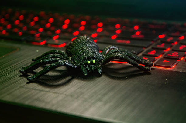 istock A realistic black spider toy with glowing green eyes is placed on a laptop keyboard with red backlighting, creating a striking contrast 2183226292