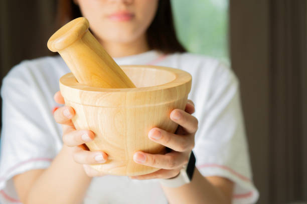 Empty wooden mortar with pestle on Asian woman hands. Kitchen tool design projects featuring traditional cooking concept.