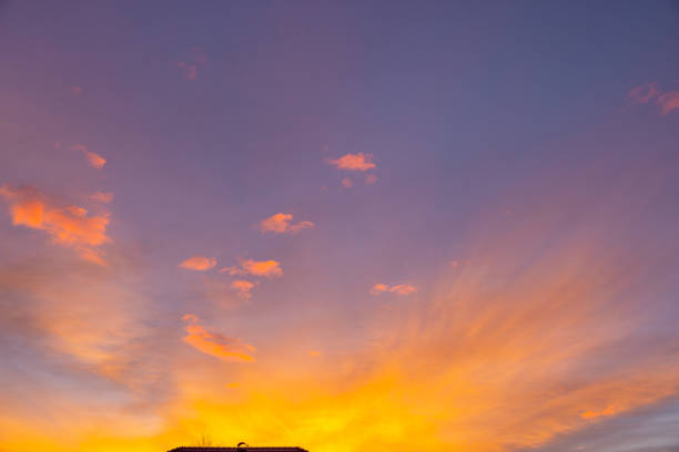 A vibrant sunset paints the sky with orange hues above a farm's outline, creating a serene backdrop to end the day.