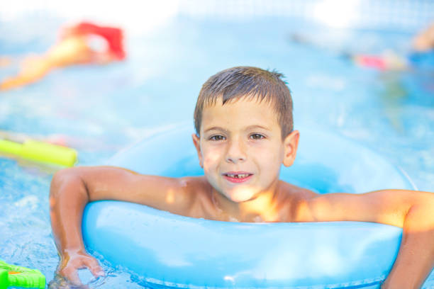 A little boy with floaties on his arms looks excited and prepared for a fun swim, captured in close-up.