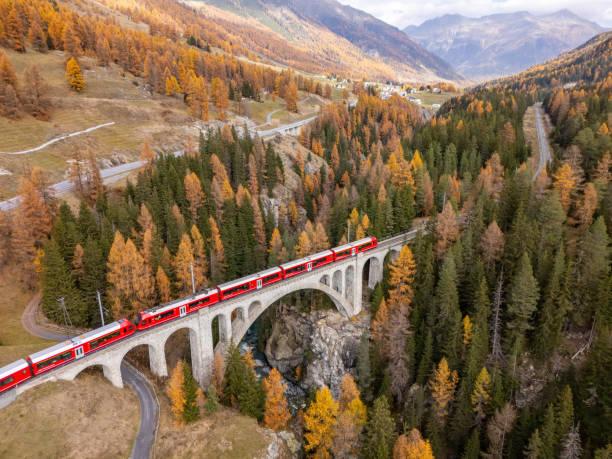 istock Red Train Crossing a Historic Stone Bridge in Swiss Alps 2183239951