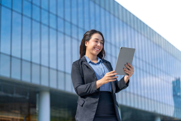 istock Asian Businesswoman Using Digital Tablet with Modern Glass Building in Background 2183240594