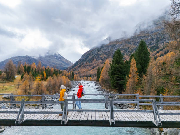 istock Two people standing on a wooden bridge over a flowing mountain river 2183244216