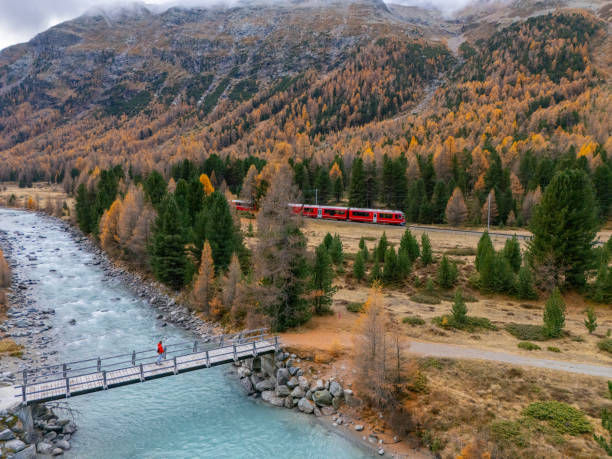istock Person on Bridge with Scenic Train Passing Through Autumnal Valley 2183244333