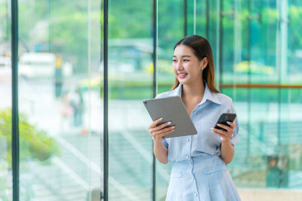 istock Young Woman Multi-tasking On Tablet and Smartphone, Looking Away Contented 2183244661