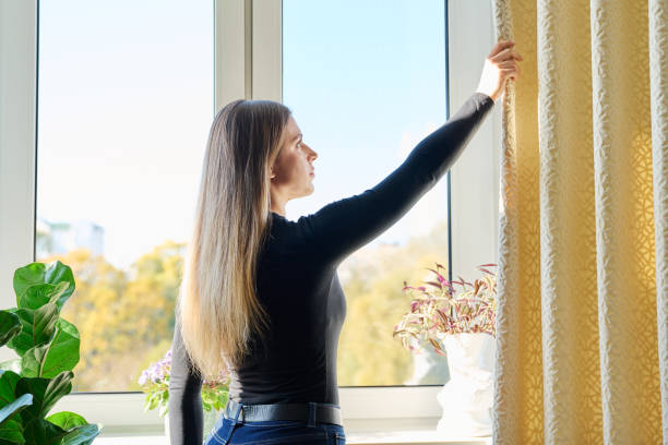 istock Young woman closing opening thick curtains on window 2183246508