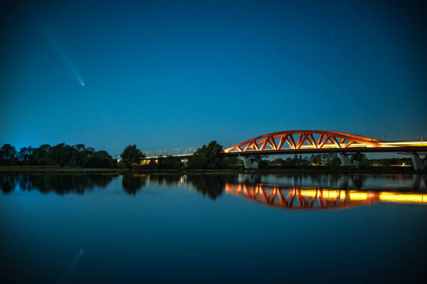 Comet C/2023 A3 or Tsuchinshan-ATLAS in the night sky over the Hanzeboog train bridge crossing the river IJsse near Zwolle in Overijssel on October 14, 2024. A train is driving over the bridge.
