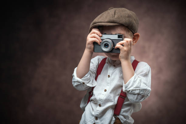 istock Boy Photographer with Retro Camera making picture against vintage background 2183252781