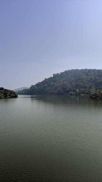 istock Serene lake surrounded by green hills under a clear sky. 2183261588