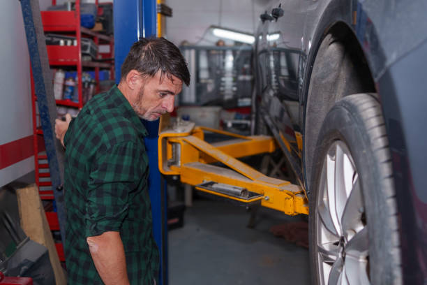 istock Mechanic elevating car on hydraulic lift in workshop 2183263879