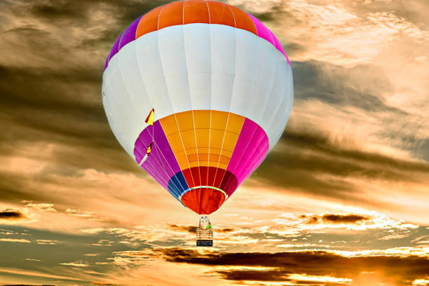 Colorful hot air balloon flying over blue sky with white clouds