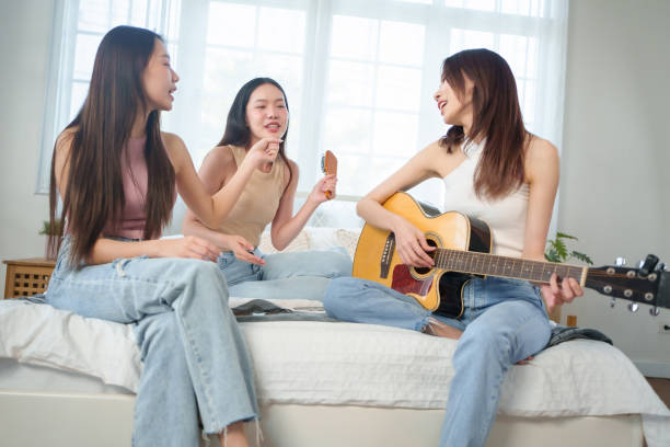 istock Three young Asian women enjoying a music session on a bed 2183270796