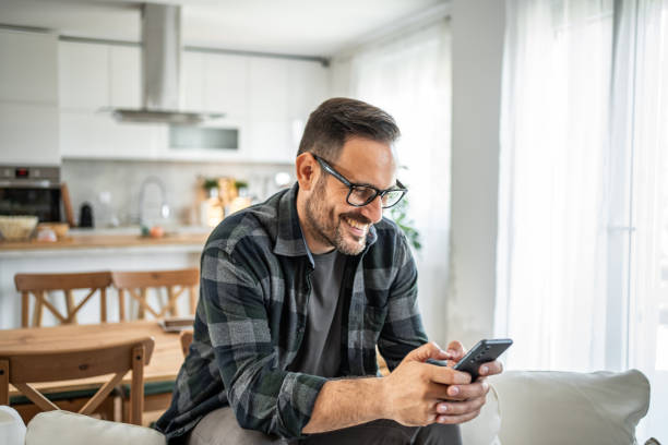 istock Positive man interacting with his smartphone, bringing a touch of joy to his home routine 2183275008