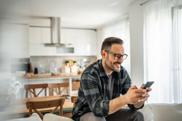 istock Positive man interacting with his smartphone, bringing a touch of joy to his home routine 2183275022