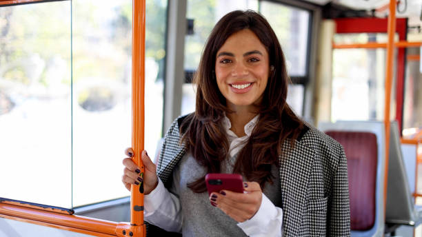 istock Young woman using her phone during a bus trip through the bustling city 2183275919