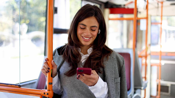 istock Young woman using her phone during a bus trip through the bustling city 2183276018