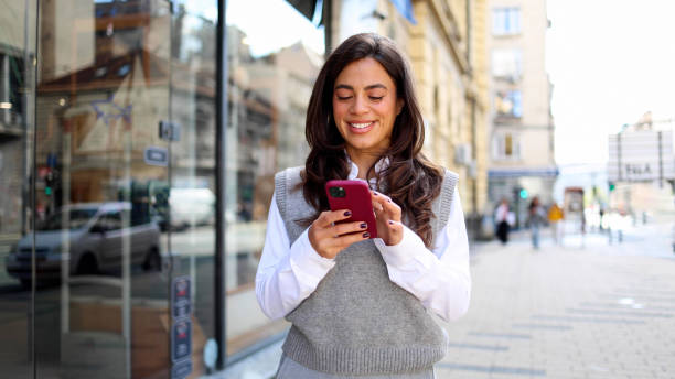 istock Happy young woman walking and using smartphone on the way 2183276297