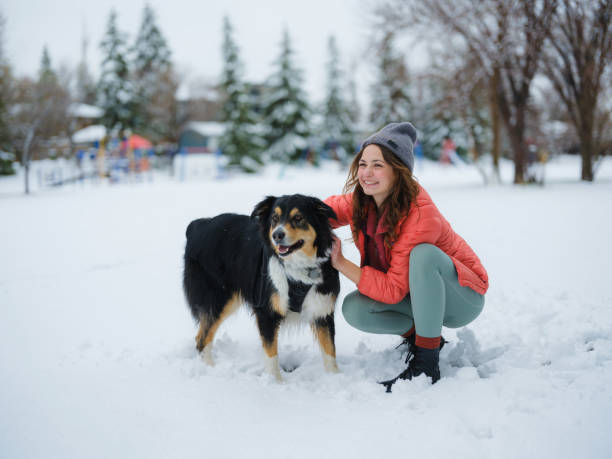 Cheerful woman in sports clothing  walking with dog in winter