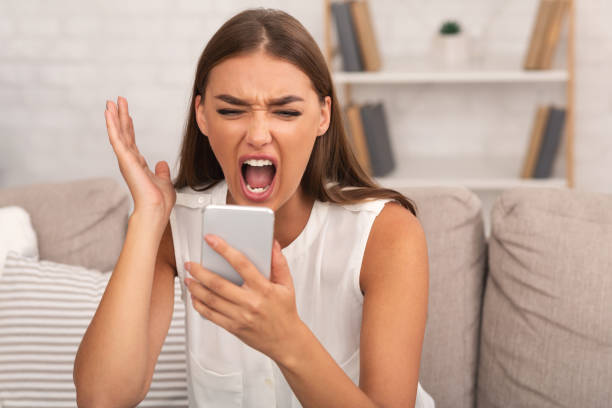 istock Furious Lady Shouting On Smartphone Sitting On Couch At Home 2183283632