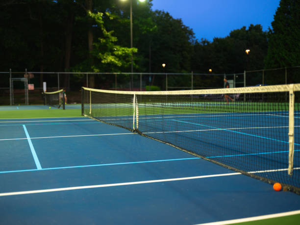 Empty blue pickleball court lit by lights at dusk
