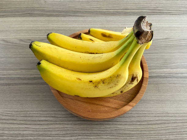 Bright yellow banana on white ceramic plate. Creative minimal composition with riple banana, top view