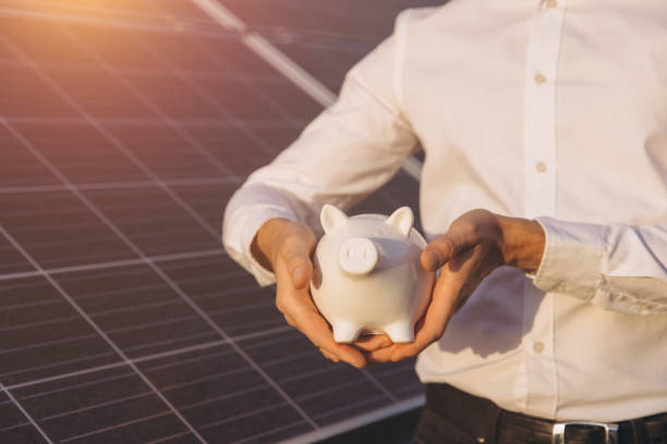 istock Businessman Holding Piggy Bank With Solar Panel Background 2183289836