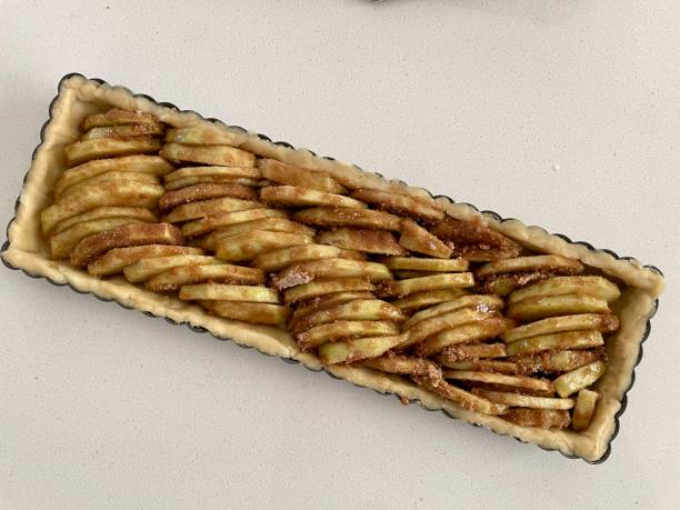Apple slices stacked in a tart pan waiting for a crumble top to be applied