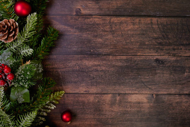 istock Festive Rustic Christmas Background Featuring Red Ornaments and Lush Pine Branches on Wood 2183292710