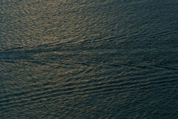 Aerial view of the dark blue ocean with textured water patterns and light reflections. Ocean wave background.