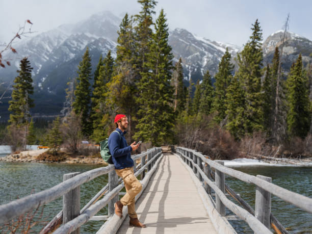 istock Man using smartphone walking on bridge at Spirit Island in Jasper National Park, Canada 2183295337
