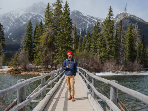 istock Man using smartphone walking on bridge at Spirit Island in Jasper National Park, Canada 2183295339